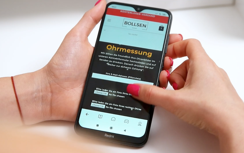 A person holds a smartphone displaying a website with BOLLSEN Earplugs Hearing Protection.