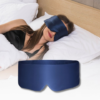 Woman resting on a bed, wearing a blue satin eye mask. Soft white pillows nearby.