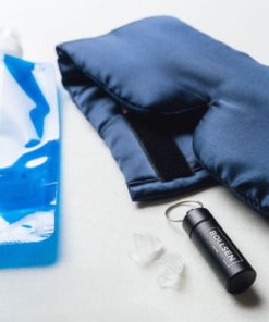 Blue water bottle, dark blue sleep mask, black keychain, and white earplugs on a surface.