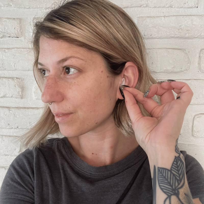 A woman inserting Life+ earplugs