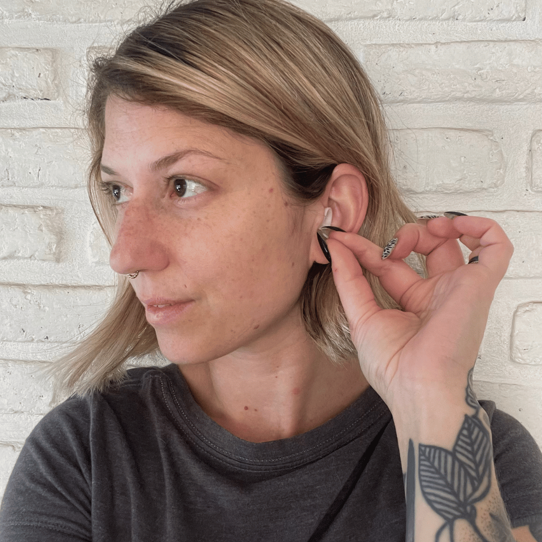 A woman inserting Life+ earplugs