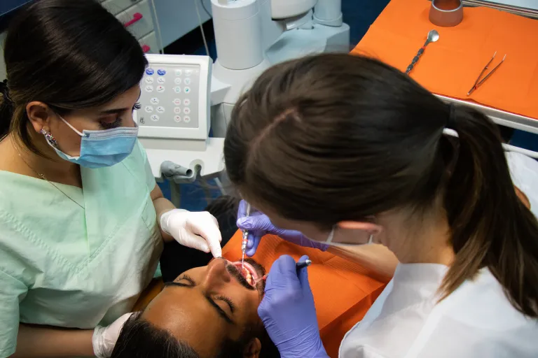 Dentist and assistant treating a patient in a Munich dental surgery, the high-speed handpiece in use at the chair