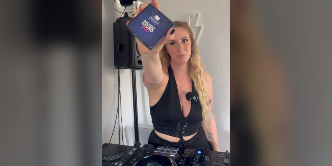 Techno DJ Nina W holding a BOLLSEN Music SoundPRO box at her decks